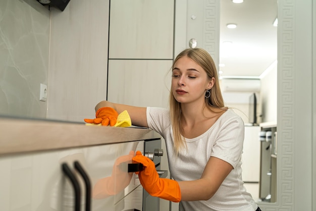 Jolie jeune femme nettoyant et désinfectant une surface de ménage de cuisine