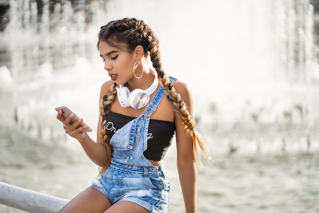 Une jolie jeune femme noire ajoute une nouvelle piste à sa playlist à l'aide d'une application mobile