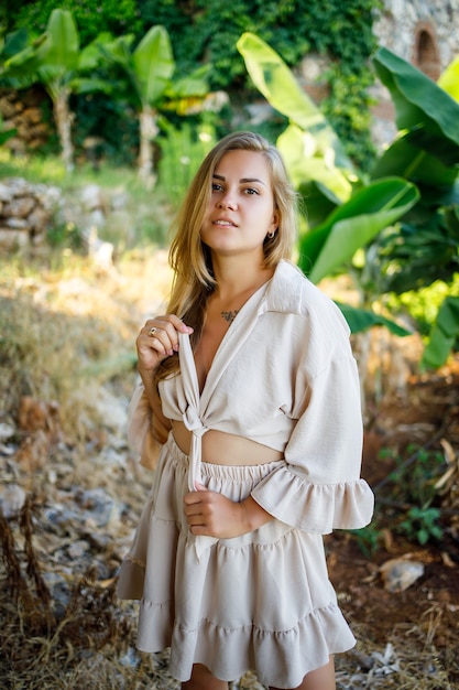 Jolie jeune femme à la peau claire se tient près des bananiers dans un parc tropical