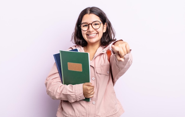 Jolie jeune femme pointant sur la caméra vous choisissant. étudiant avec le concept de livres