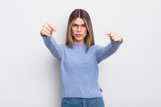 Jolie jeune femme pointant vers l'avant à la caméra avec les deux doigts et une expression de colère, vous disant de faire votre devoir