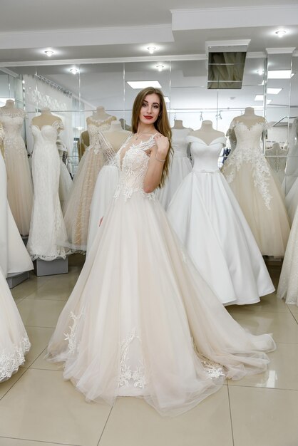 Jolie jeune femme portant une robe de mariée en boutique de mariée