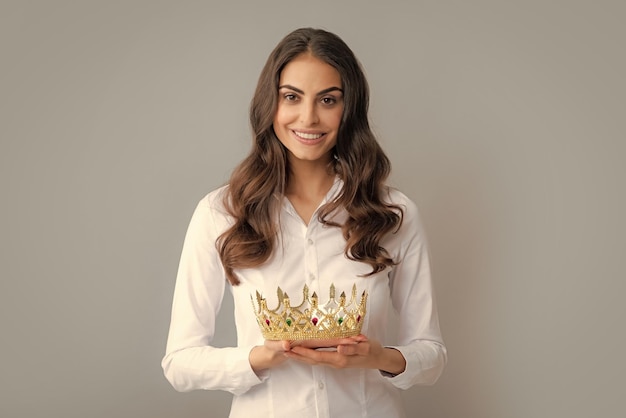 Jolie jeune femme porte une couronne isolée sur fond gris Fille avec arrogance de la couronne dorée et concept de statut privilégié de succès et de rêves