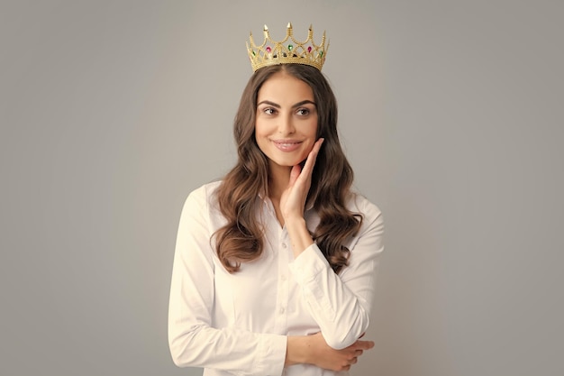 Jolie jeune femme porte une couronne isolée sur fond gris Fille avec arrogance de la couronne dorée et concept de statut privilégié de succès et de rêves