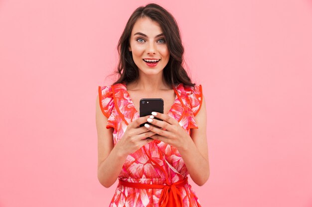 Jolie jeune femme posant sur un mur isolé à l'aide de téléphone mobile.