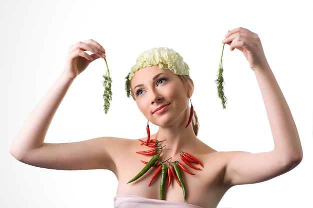 Jolie jeune femme posant avec des poivrons rouges et verts près du cou