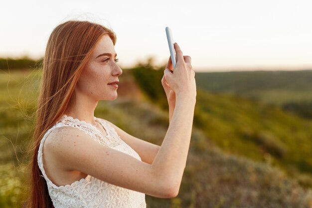 Jolie jeune femme prenant des photos de campagne