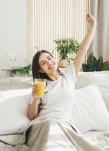 Une jolie jeune femme qui s'étend le matin avec un verre de jus