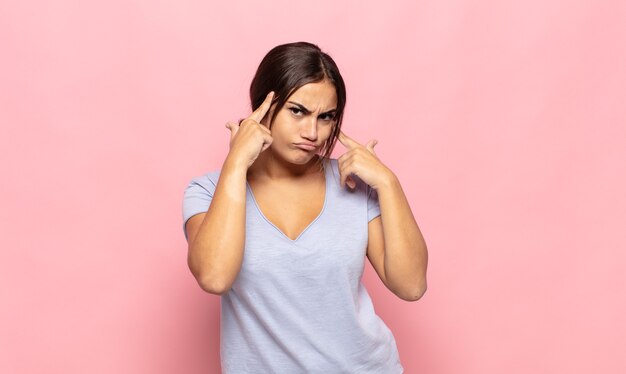 Jolie jeune femme à la recherche concentrée et réfléchie à une idée, imaginant une solution à un défi ou un problème