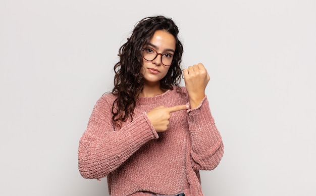 Jolie jeune femme à la recherche d'impatience et en colère, pointant sur la montre, demandant la ponctualité