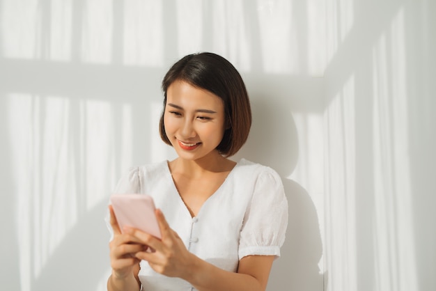 Jolie jeune femme regardant la caméra et debout au mur