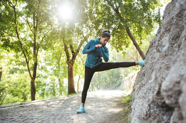 Jolie jeune femme de remise en forme portant des vêtements de sport exerçant à l'extérieur, faisant des exercices d'étirement