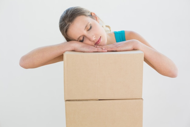 Jolie jeune femme reposant la tête sur une pile de boîtes