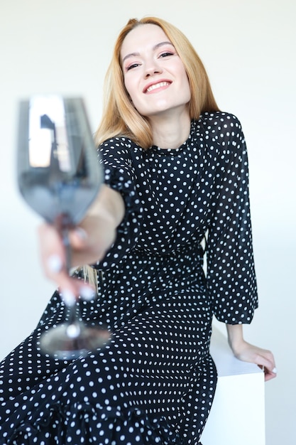 Jolie jeune femme en robe noire à pois avec verre