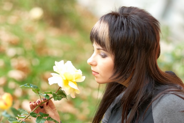 Jolie jeune femme avec une rose jaune dans le jardin
