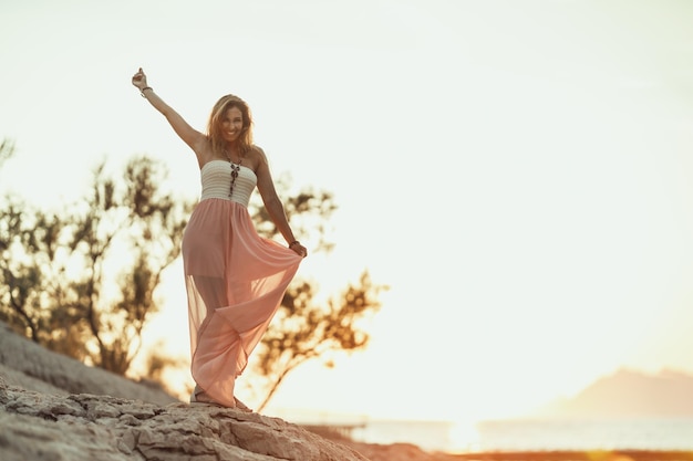 Une jolie jeune femme s'amuse et danse tout en profitant de vacances d'été au bord de la mer.