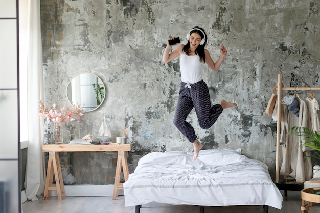 Photo jolie jeune femme sautant dans son lit