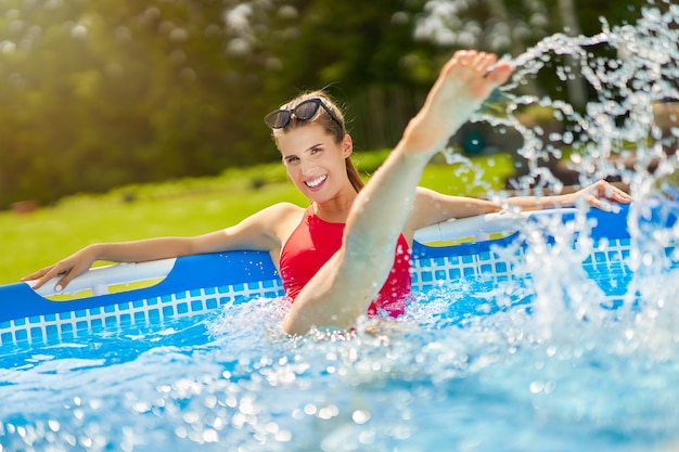 une jolie jeune femme se détendre sur la piscine dans l'arrière-cour