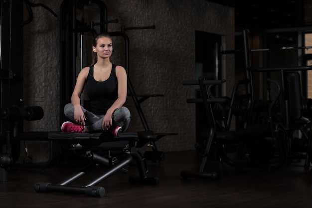 Jolie jeune femme se reposant dans la salle de gym après l'exercice