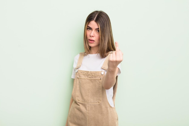 Jolie jeune femme se sentant en colère, agacée, rebelle et agressive, retournant le majeur, ripostant