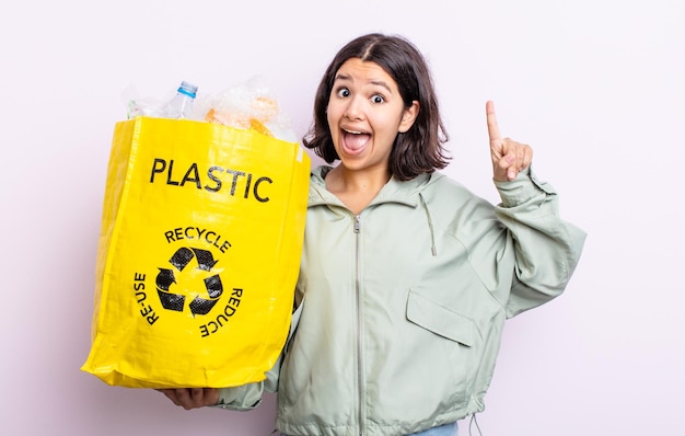 Jolie jeune femme se sentant comme un génie heureux et excité après avoir réalisé une idée. concept de recyclage du plastique