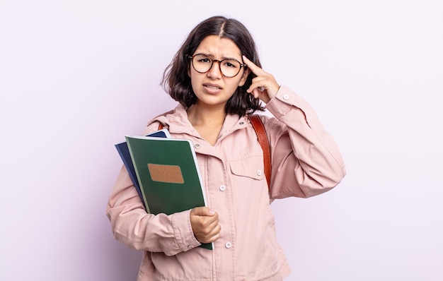 jolie jeune femme se sentant confuse et perplexe, montrant que vous êtes fou. étudiant avec concept de livres