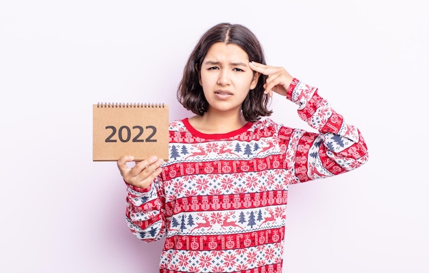 Jolie jeune femme se sentant confuse et perplexe, vous montrant que vous êtes fou. concept de calendrier 2022