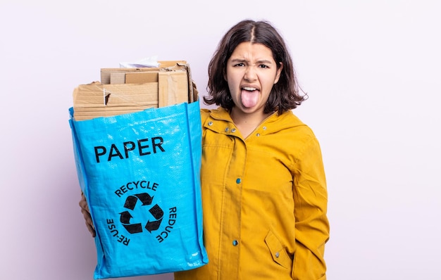 Jolie jeune femme se sentant dégoûtée et irritée et tirer la langue. concept de recyclage du papier