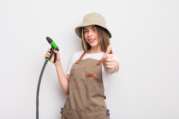 Jolie jeune femme se sentant fière et souriante positivement avec le concept d'arrosage du jardinier