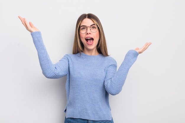 Jolie jeune femme se sentant heureuse, étonnée, chanceuse et surprise, célébrant la victoire avec les deux mains en l'air