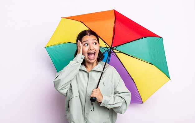 Jolie jeune femme se sentant heureuse, excitée et surprise. concept de pluie et de parapluie