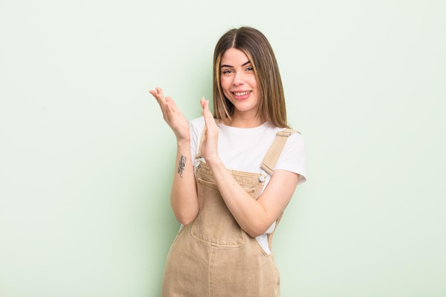 Jolie jeune femme se sentant heureuse et réussie en souriant et en frappant des mains en disant félicitations avec des applaudissements