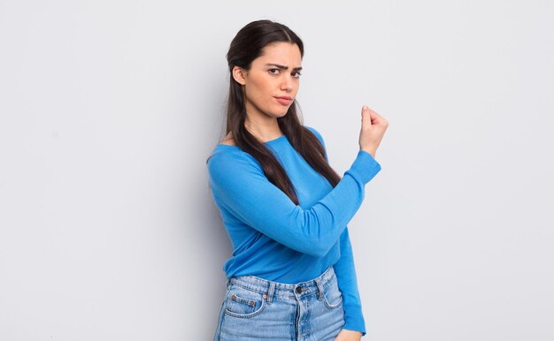 Jolie jeune femme se sentant heureuse, satisfaite et puissante en forme de flexion et biceps musclés à la recherche de force après la salle de sport