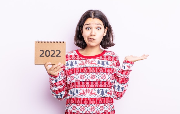 Jolie jeune femme se sentant perplexe, confuse et doutante. concept de calendrier 2022