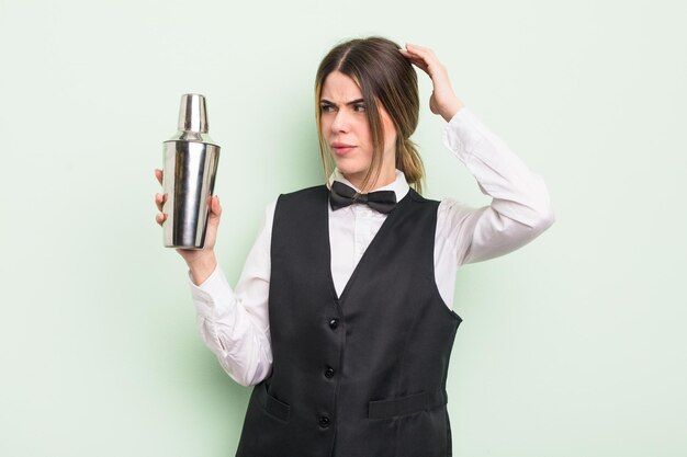 Jolie jeune femme se sentant perplexe et confuse, se grattant la tête. concept de barman à cocktails