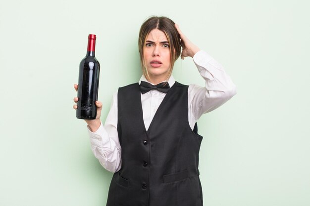 Jolie jeune femme se sentant stressée anxieuse ou effrayée avec les mains sur le maître d'hôtel et le concept de bouteille de vin