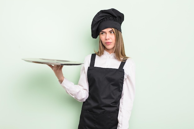 Jolie jeune femme se sentant triste, bouleversée ou en colère et regardant sur le côté. chef avec un concept de plateau