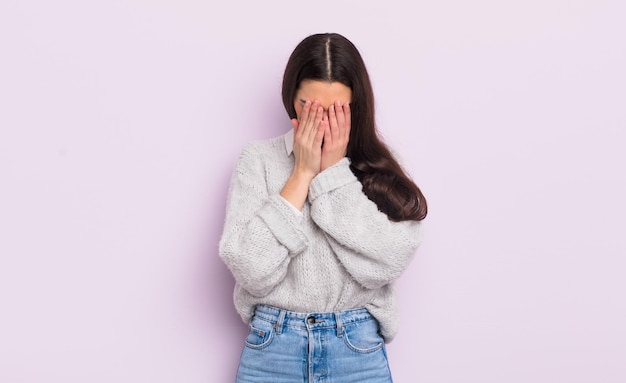 Jolie jeune femme se sentant triste, frustrée, nerveuse et déprimée, couvrant le visage des deux mains, pleurant