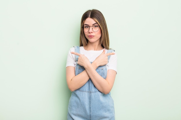 Jolie jeune femme semblant perplexe et confuse, peu sûre et pointant dans des directions opposées avec des doutes