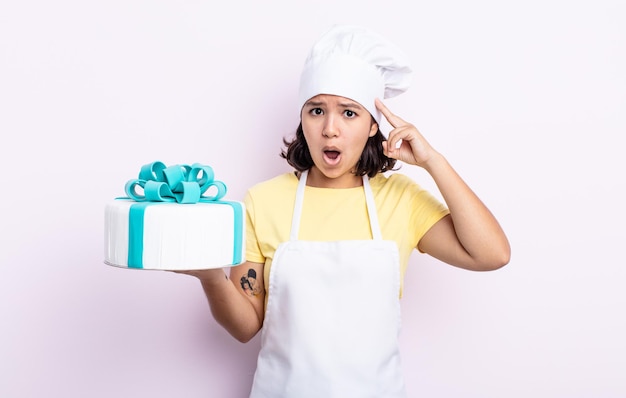 Jolie jeune femme semblant surprise, réalisant une nouvelle pensée, idée ou concept. chef cuisinant un gâteau