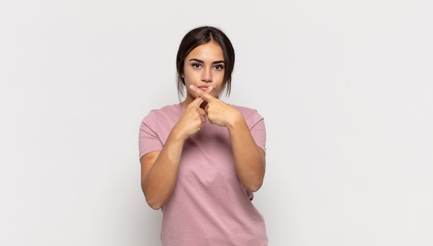 Jolie jeune femme à la sérieuse et mécontente avec les deux doigts croisés à l'avant dans le rejet, demandant le silence