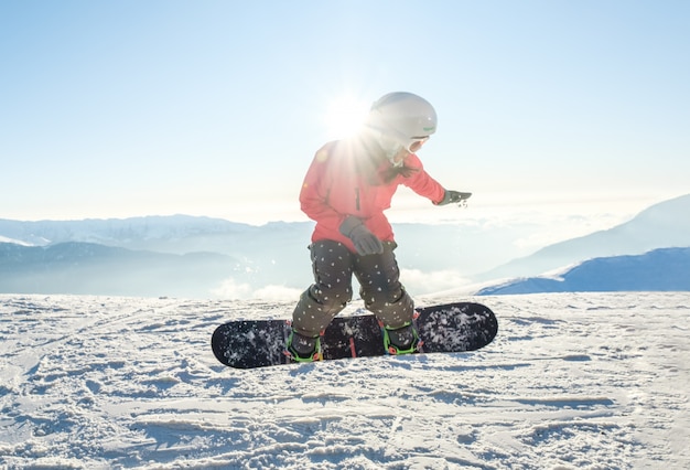 Jolie jeune femme sur le snowboard sautant par-dessus la pente