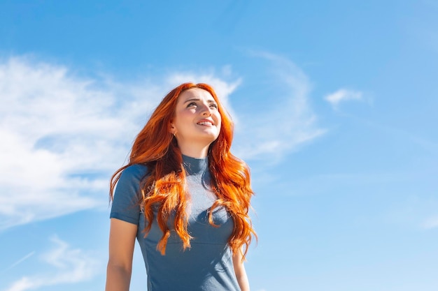 Jolie jeune femme souriante regardant le ciel avec espace de copie dans une rue urbaine