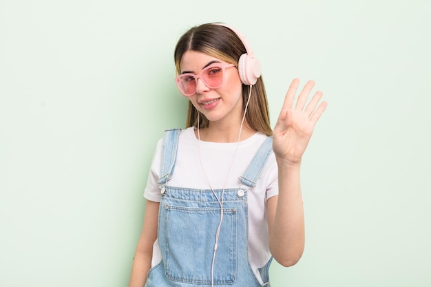 Jolie jeune femme souriante et sympathique, montrant le numéro quatre. concept d'écoute de musique