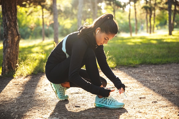 Jolie jeune femme sportive attachant des lacets au parc