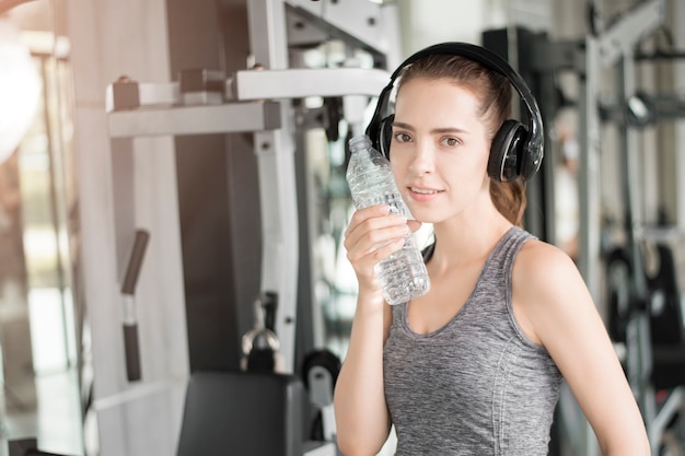 Jolie jeune femme sportive boit de l&#39;eau dans une salle de sport, Mode de vie sain