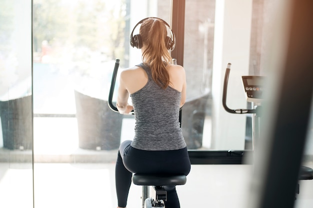 Jolie jeune femme sportive est un exercice à vélo dans une salle de sport