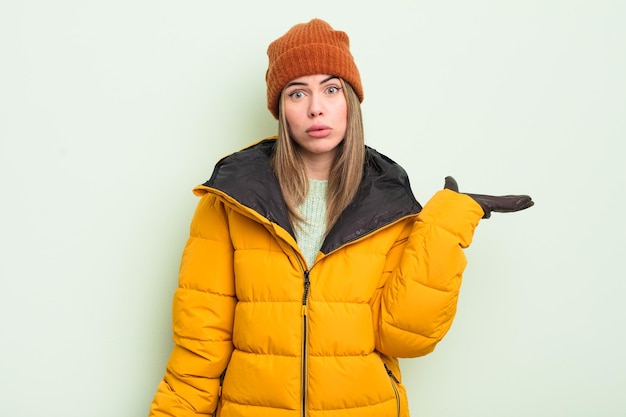 Jolie jeune femme à la surprise et choquée avec la mâchoire tombée tenant un concept de temps froid d'objet