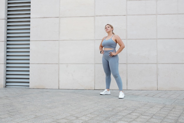 Jolie jeune femme taille plus en soutien-gorge de sport et leggings debout à l'extérieur après le jogging