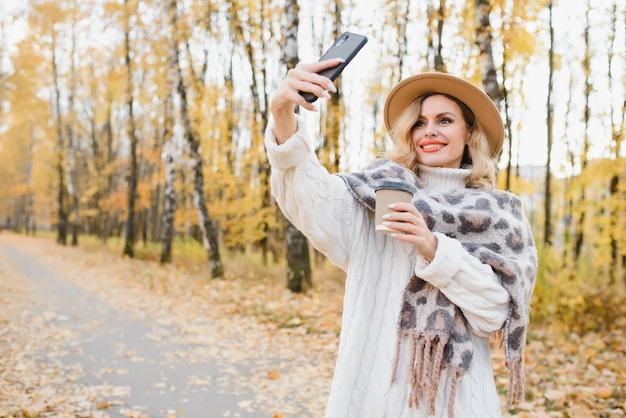 Jolie jeune femme avec une tasse de café dans le parc en automne